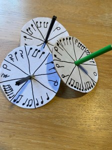 The picture shows 3 homemade musical spinners complete with rhythm patterns hand written on them. 
