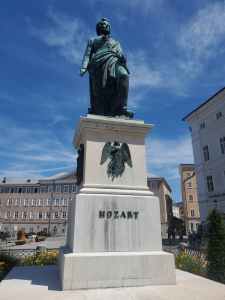 The picture shows a statue of Mozart under a bright blue sky.