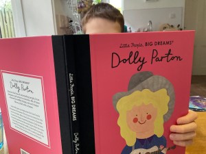 You can see the book about Dolly Parton open  with the top of a boy's head just over the top of the book, concentrating on his reading.
