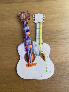 Two wooden guitar shapes already decorated by hand.