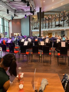 The stage area set with chairs and music stands ready for the performance. A bar area table is in the foreground with a family's drinks on it.