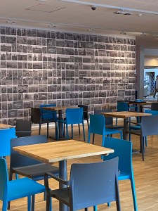 An exhibition wall runs all the way along the side of one of the seating areas customers can use in the front of house area.