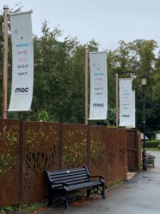 Metal decorative fencing and banners for MAC at the park entrance to the venue. A bench is available right next to this decorative fencing to sit on and watch the world go by. 