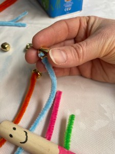 Threading a small gold bell through the pipe cleaner