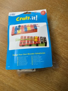 The Baker Ross Decorate Your Own Wooden xylophones kit. The cover of the kit has 2 xylophones already decorated in bright primary colours on it, giving you ideas of how you can decorate yours. One has red, yellow and blue stripes, and one looks a bit like maybe a ladybird.
